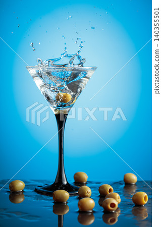 Martini with green olives on a wet table. Martini with green olives on a wet table. 140355501