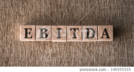 EBITDA text written on wooden block on brown background. Short for earning before interest taxes depreciation and amortization EBITDA text written on wooden block on brown background. Short for earning before interest taxes depreciation and amortization 140355535