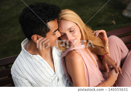 Couple enjoying a tender moment in a sunny park setting Couple enjoying a tender moment in a sunny park setting 140355631