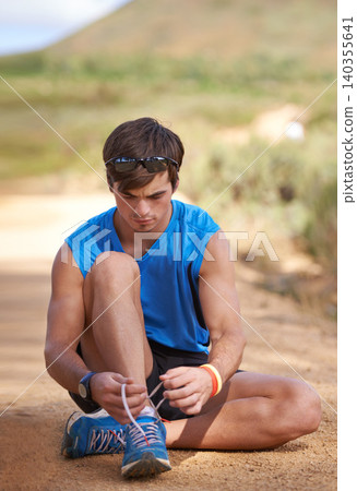 Tie, runner or man with shoe lace for fitness training, walking exercise or workout on path or sand. Running, wellness or male sports athlete with footwear ready to start outdoor hiking in nature Tie, runner or man with shoe lace for fitness training, walking exercise or workout on path or sand. Running, wellness or male sports athlete with footwear ready to start outdoor hiking in nature 140355641