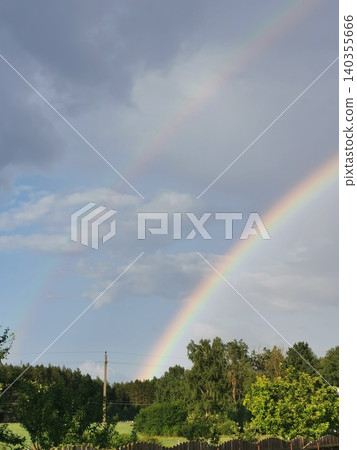 Double rainbow in sky over the forest and village. Close up. Landscape Double rainbow in sky over the forest and village. Close up. Landscape 140355666