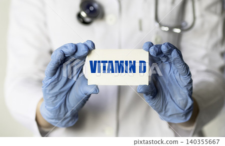 VITAMIN D written on a card in doctors hands. VITAMIN D written on a card in doctors hands. 140355667