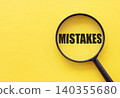 The word mistakes is written on a magnifying glass on a yellow background. 140355680