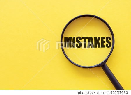 The word mistakes is written on a magnifying glass on a yellow background. The word mistakes is written on a magnifying glass on a yellow background. 140355680