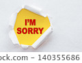 Top view of white torn paper and the text I'M SORRY on a yellow background. 140355686