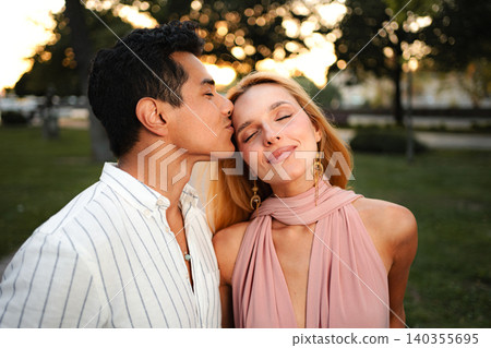 Couple shares a tender moment in a serene park at sunset Couple shares a tender moment in a serene park at sunset 140355695