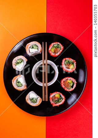 Creative flat lay of assorted sushi rolls on circle plate over red and black background 140355703