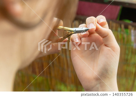 Macro shot of female hands doing precise nail care on terrace backdrop Macro shot of female hands doing precise nail care on terrace backdrop 140355726