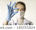 Doctor holding a pill, looking at it and giving it as a treatment to the patient 140355824