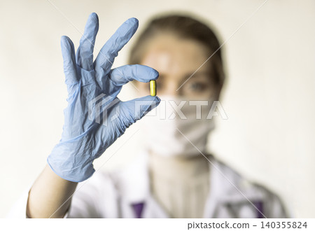 Doctor holding a pill, looking at it and giving it as a treatment to the patient 140355824