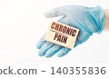 The doctor's hand in a blue glove shows wooden cubes with the text "Chronic pain". Medical concept. 140355836
