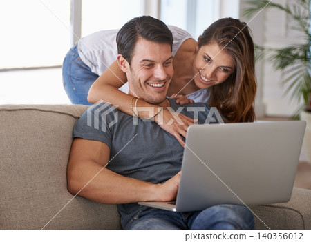 Laptop, smile and woman hugging man on sofa networking on social media, website or internet. Happy, love and female person embracing husband reading online blog with computer in living room at home. 140356012