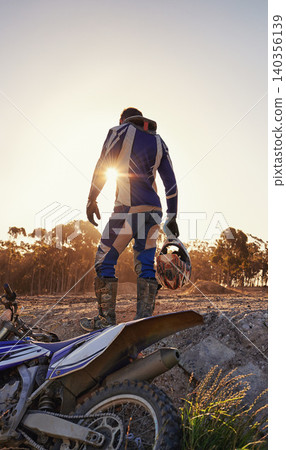 Motorcycle, sports and danger with back view of biker person outdoor, sunlight with uniform for riding on dirt track. Speed, power and risk with motorbike, transportation and adventure for adrenaline Motorcycle, sports and danger with back view of biker person outdoor, sunlight with uniform for riding on dirt track. Speed, power and risk with motorbike, transportation and adventure for adrenaline 140356139