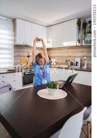 Female Doctor Stretching While Working From Home in Kitchen Female Doctor Stretching While Working From Home in Kitchen 140356213