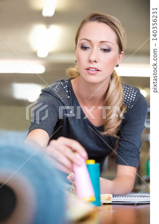Business, woman and designer with textile for fashion with fabric check and sewing equipment at work. Creative, person and tailor or seamstress with thread for pattern, inspiration and design studio Business, woman and designer with textile for fashion with fabric check and sewing equipment at work. Creative, person and tailor or seamstress with thread for pattern, inspiration and design studio 140356231