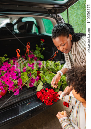 Mother and child putting flowers in car trunk 140356275