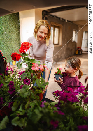 Mother and daughter bonding while planting flowers outdoors 140356277