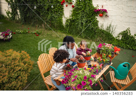 Family enjoying gardening together planting flowers in backyard Family enjoying gardening together planting flowers in backyard 140356283