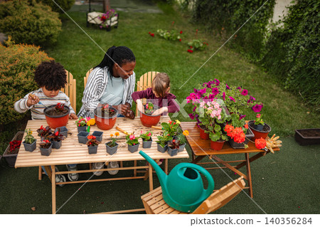 Multi-ethnic family potting flowers together in backyard garden Multi-ethnic family potting flowers together in backyard garden 140356284