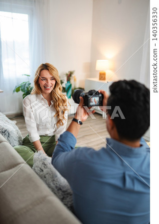 Photographer taking pictures of a young woman posing indoors 140356330