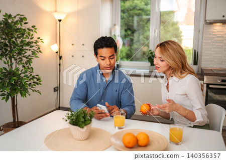 Young couple having breakfast and talking in kitchen Young couple having breakfast and talking in kitchen 140356357