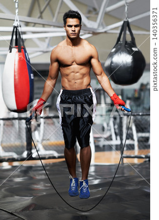 Portrait, fitness and man skipping in gym for fight preparation, training or boxing cardio. Exercise, workout or strong body of shirtless young athlete with jump rope for combat sports competition 140356371