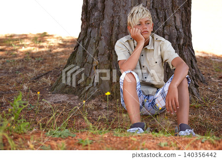 Boy, bored and depression by tree with anxiety, mental health or stress on grass in nature. Young male person, child or teenager resting on break by wood stump in loneliness, childhood or left out Boy, bored and depression by tree with anxiety, mental health or stress on grass in nature. Young male person, child or teenager resting on break by wood stump in loneliness, childhood or left out 140356442