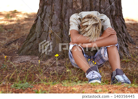 Sad boy, stress and depression by tree with anxiety, mental health or bored on grass in nature. Male person, child or teenager resting head on arms by stump in loneliness, childhood or left out Sad boy, stress and depression by tree with anxiety, mental health or bored on grass in nature. Male person, child or teenager resting head on arms by stump in loneliness, childhood or left out 140356445