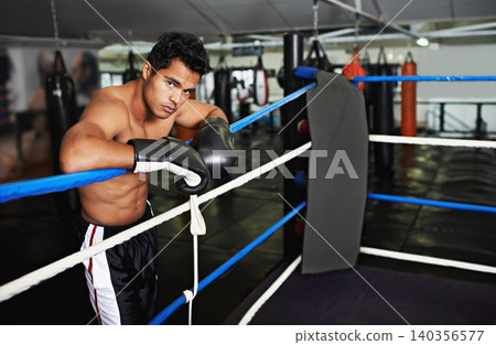 Fitness, portrait and man boxer in gym for exercise, workout and combat training for competition. Cardio, health and shirtless male athlete fighter in boxing ring with gloves in sports center. Fitness, portrait and man boxer in gym for exercise, workout and combat training for competition. Cardio, health and shirtless male athlete fighter in boxing ring with gloves in sports center. 140356577