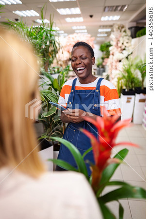 Florist laughing while using a smartphone in a flower shop Florist laughing while using a smartphone in a flower shop 140356608