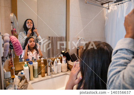 A woman is brushing her hair in front of a mirror A woman is brushing her hair in front of a mirror 140356637