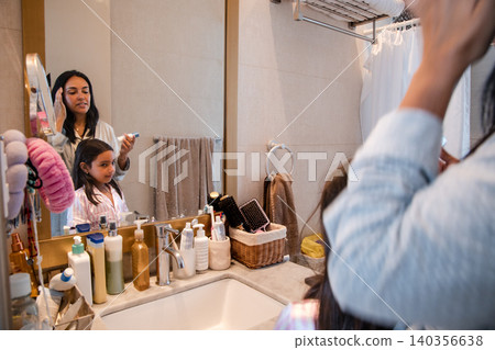 A woman is brushing her teeth in front of a mirror A woman is brushing her teeth in front of a mirror 140356638
