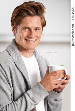 Smile, portrait and man with cup of coffee in kitchen of home for relax, health and wellness. Happy, confident and young male person drinking cappuccino, espresso or latte in modern apartment. Smile, portrait and man with cup of coffee in kitchen of home for relax, health and wellness. Happy, confident and young male person drinking cappuccino, espresso or latte in modern apartment. 140356800