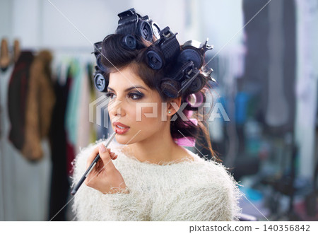 Woman, face or hair curlers with lipstick for beauty in salon with haircare, self care or cosmetology. Model, person or cosmetics brush for morning routine or getting ready for wellness and grooming Woman, face or hair curlers with lipstick for beauty in salon with haircare, self care or cosmetology. Model, person or cosmetics brush for morning routine or getting ready for wellness and grooming 140356842