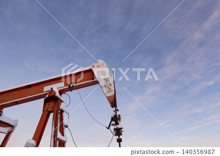 Oil Pumpjack's horsehead against blue and pink sky. 140356987