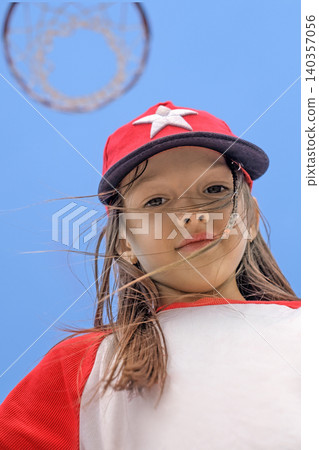 Portrait of a cute girl in a sports cap against the sky and a basketball basket Portrait of a cute girl in a sports cap against the sky and a basketball basket 140357056