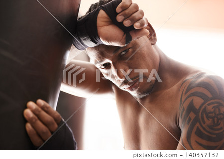Punching bag, portrait and tired black man in gym for boxing challenge, fight and competition training. Power, muscle and exhausted face of champion boxer at workout with fatigue in sports club. Punching bag, portrait and tired black man in gym for boxing challenge, fight and competition training. Power, muscle and exhausted face of champion boxer at workout with fatigue in sports club. 140357132