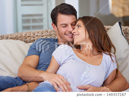 Happy couple, relax and hug on sofa for comfort connection in Florida for bonding vacation, resting or marriage. Man, woman and embrace on apartment couch for together commitment, love or loyalty 140357287