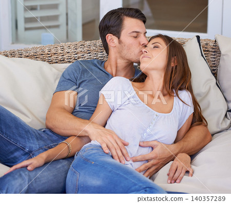 Kiss, love and couple relaxing on sofa for bonding in living room at apartment together. Happy, resting and young man and woman laying on couch for romance and marriage in lounge at modern home. 140357289