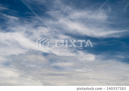 Calm atmosphere with cloud layers. Gentle clouds stretch across tranquil sky. Peaceful sky presents calm and expansive scene filled with gentle clouds and subtle colors 140357383