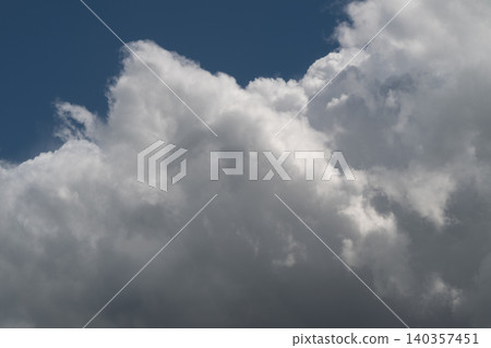 Bright sunlit cumulus cloud towering against blue backdrop, voluminous white formations with luminous edges and high contrast perfect for uplifting nature visuals 140357451