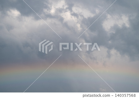 Subtle rainbow appears. Delicate arc under cloudy sky. Gentle rainbow stretches across gray clouds softly. Faint rainbow curves beneath rain clouds inspiring quiet wonder Subtle rainbow appears. Delicate arc under cloudy sky. Gentle rainbow stretches across gray clouds softly. Faint rainbow curves beneath rain clouds inspiring quiet wonder 140357568