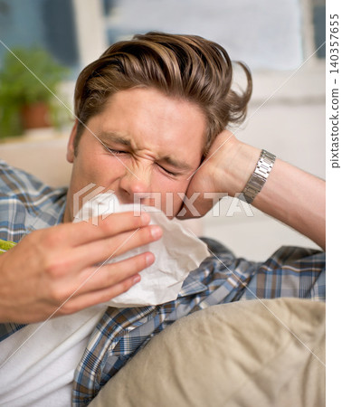 Sick, flu or man sneezing into tissue on sofa with cold, virus or hay fever at home. Influenza, allergies or person with toilet paper for viral infection, bacteria or coughing with sinusitis in house Sick, flu or man sneezing into tissue on sofa with cold, virus or hay fever at home. Influenza, allergies or person with toilet paper for viral infection, bacteria or coughing with sinusitis in house 140357655