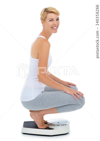 Woman, portrait and on scale in studio for weight loss, healthcare and wellness for vitality. Female person, diet and check calories for slim body for self care and happy on a white background Woman, portrait and on scale in studio for weight loss, healthcare and wellness for vitality. Female person, diet and check calories for slim body for self care and happy on a white background 140358266
