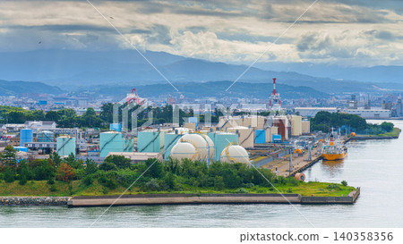 Kanazawa, Japan - Oct 6 2024, panoramic aerial view from water of the Kanazawa Port Liquefied Natural Gas Terminal, with Kanazawa cityscape and mountains in background, at daytime, Kanazawa, Japan Kanazawa, Japan - Oct 6 2024, panoramic aerial view from water of the Kanazawa Port Liquefied Natural Gas Terminal, with Kanazawa cityscape and mountains in background, at daytime, Kanazawa, Japan 140358356