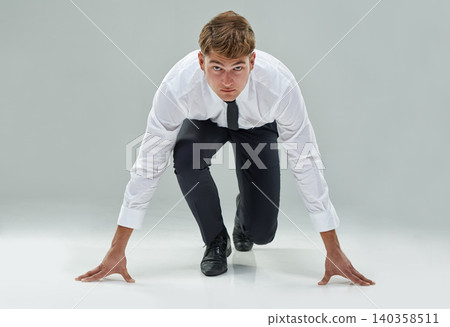 Portrait, competitive businessman and starting position on studio background to chase deadline, target or deal in business. Male model, corporate person or lawyer in running pose to race or challenge Portrait, competitive businessman and starting position on studio background to chase deadline, target or deal in business. Male model, corporate person or lawyer in running pose to race or challenge 140358511