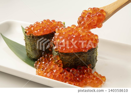 壽司盛放在白色盤子裡,鮭魚籽軍艦捲配木製鏟子。 壽司盛放在白色盤子裡,鮭魚籽軍艦捲配木製鏟子。 140358610