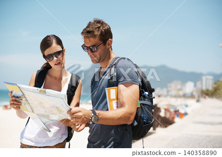 Couple, map and reading with direction at beach, summer and ideas to check path on vacation. Woman, man and chart for location, landmark and travel with search on sidewalk, sea and nature in Italy 140358890