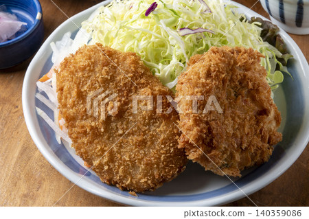 Two potato croquettes served on a plate, accompanied by a side of shredded cabbage salad. Two potato croquettes served on a plate, accompanied by a side of shredded cabbage salad. 140359086