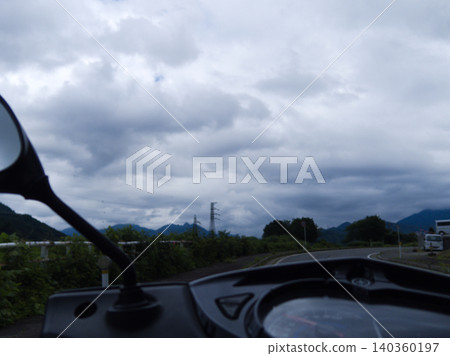 一位摩托車騎士在陰天沿著山路行駛的視角。 140360197